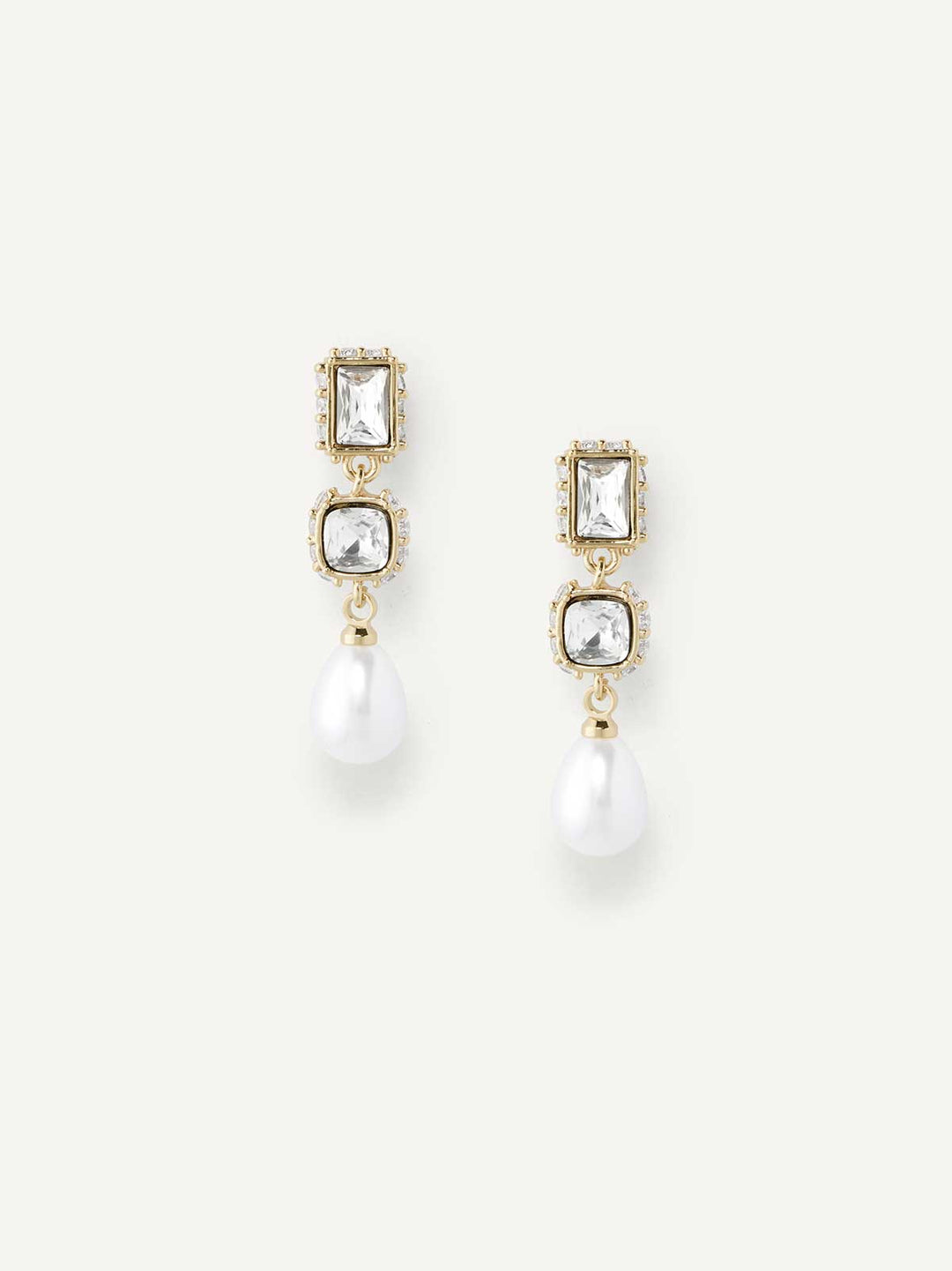 Pair of gold earrings with clear gemstones and a pearl drop on a white background