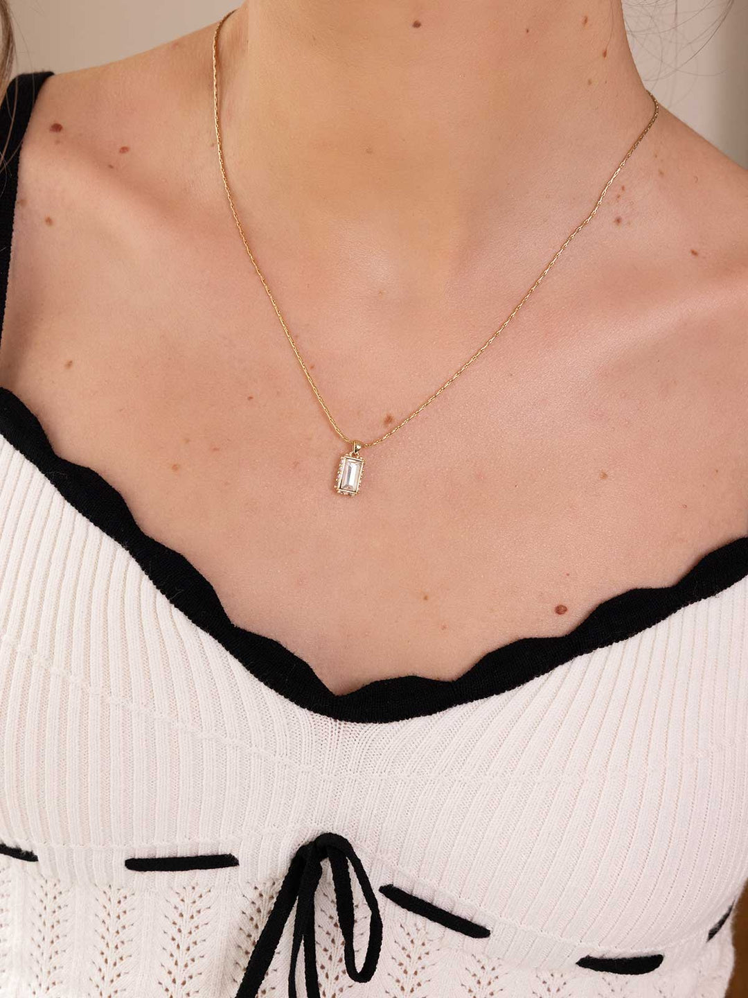 Necklace with a pendant worn by a person, focusing on the jewelry.